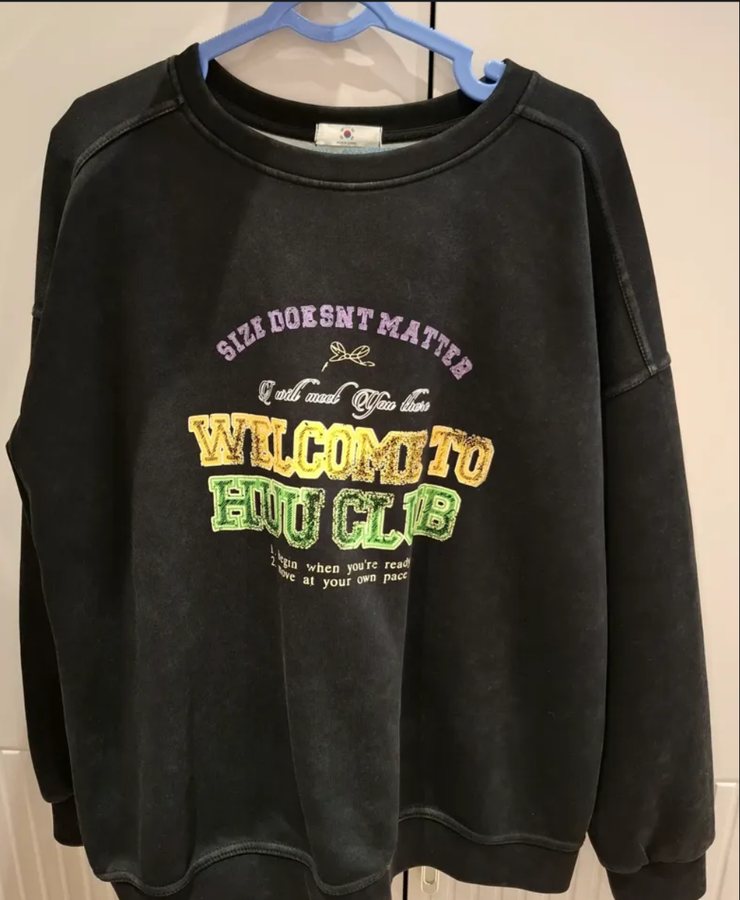 Black sweatshirt with a printed slogan on a hanger